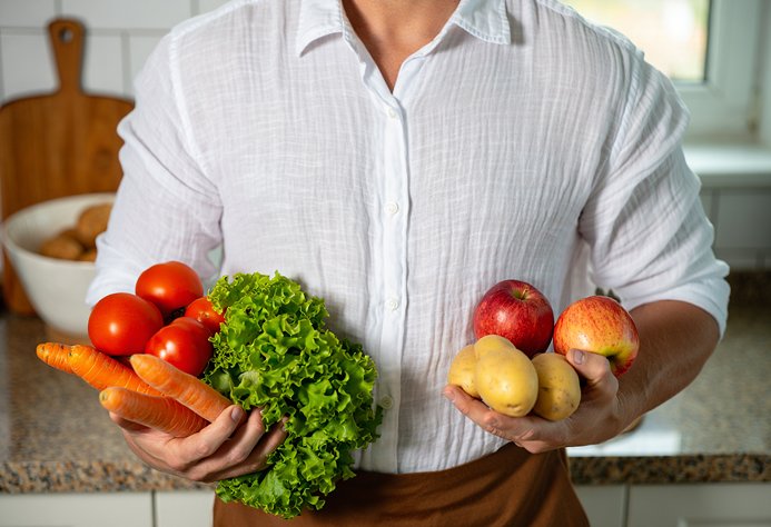 Мужчина держит овощи и фрукты
